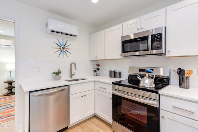 kitchen with white cabinets, stainless steel appliances, a wall unit AC, and sink