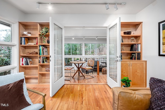 living area featuring rail lighting, light wood-type flooring, and french doors