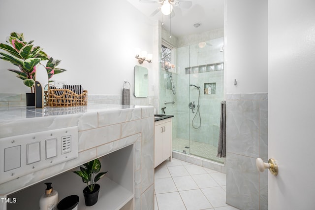 bathroom with tile walls, vanity, a shower with door, ceiling fan, and tile patterned flooring