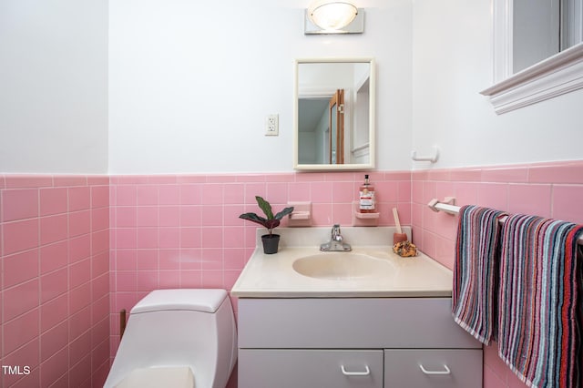 bathroom with vanity, toilet, and tile walls