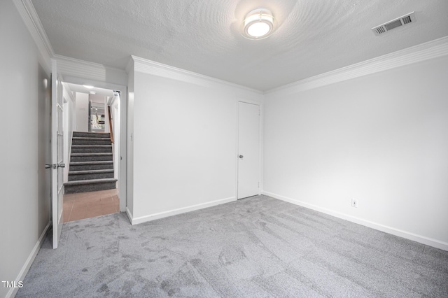 unfurnished bedroom featuring crown molding, light colored carpet, a closet, and a textured ceiling