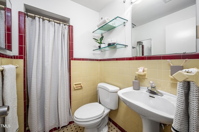 bathroom with tile walls, sink, toilet, and a shower with shower curtain