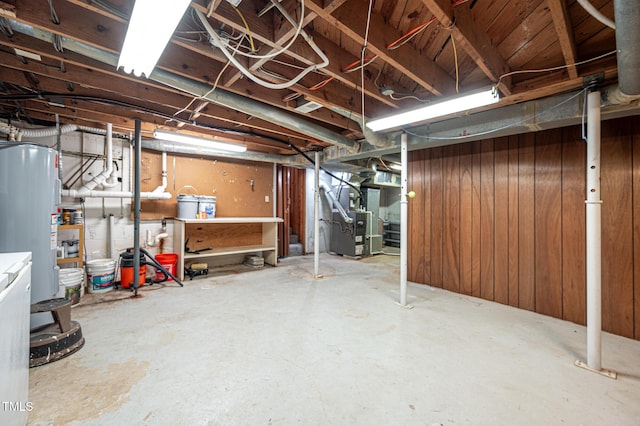 basement with water heater, wooden walls, and heating unit