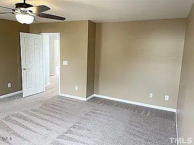 carpeted spare room featuring ceiling fan