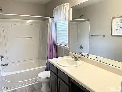 full bathroom with shower / tub combo with curtain, vanity, wood-type flooring, and toilet