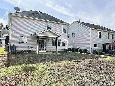 back of house featuring central air condition unit and a lawn