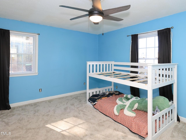 bedroom featuring multiple windows, light colored carpet, and ceiling fan