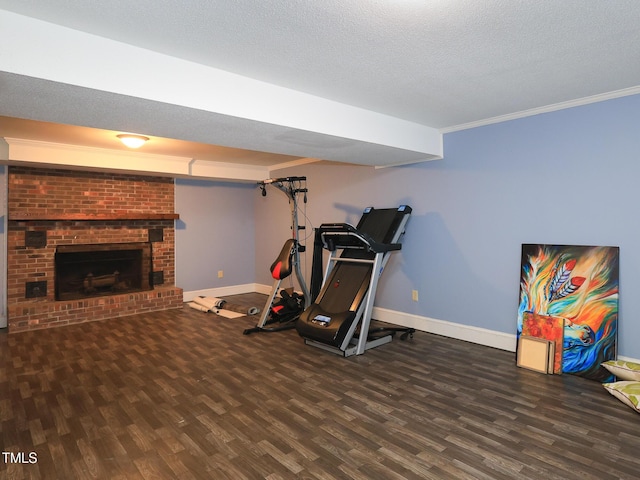 workout area featuring a fireplace, dark hardwood / wood-style flooring, a textured ceiling, and ornamental molding