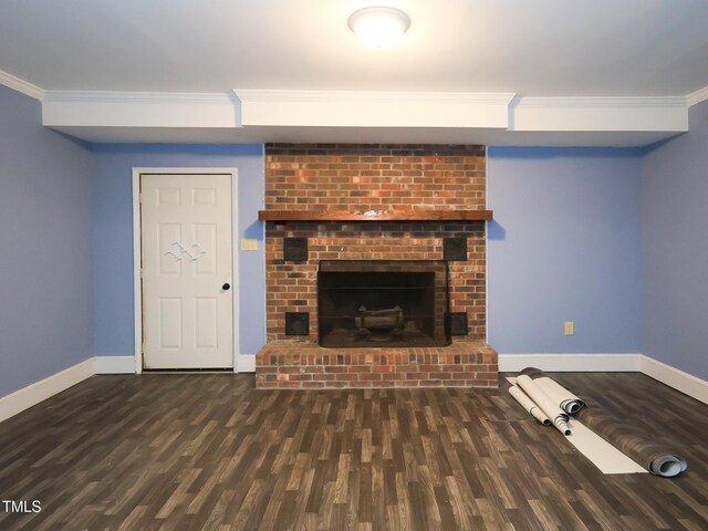 unfurnished living room with dark hardwood / wood-style floors, a brick fireplace, and crown molding