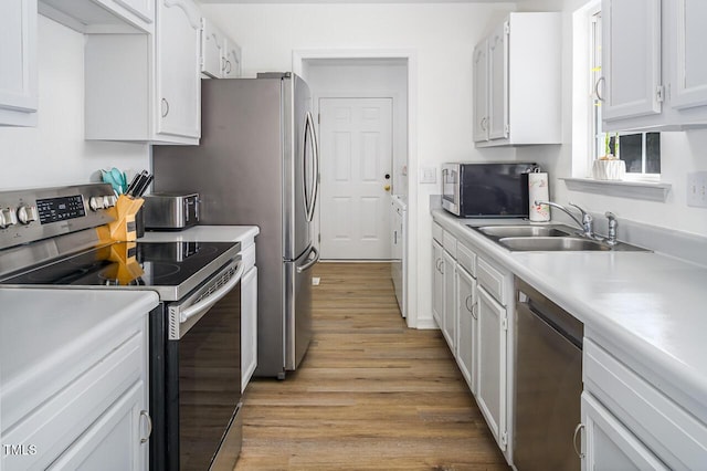 kitchen featuring white cabinets, light wood-type flooring, stainless steel appliances, and sink