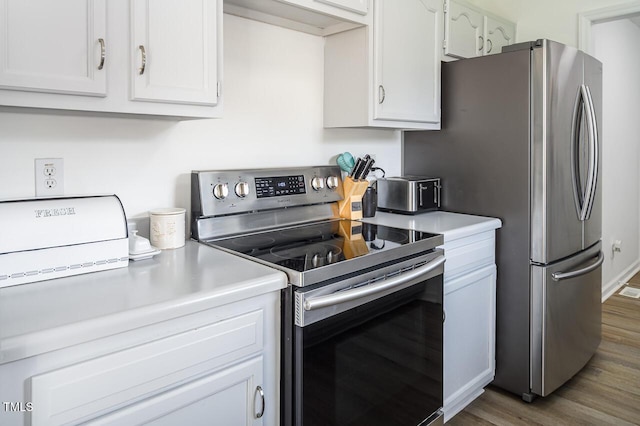 kitchen with appliances with stainless steel finishes, white cabinetry, and dark wood-type flooring