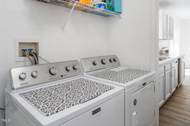 clothes washing area with light hardwood / wood-style flooring and washing machine and clothes dryer