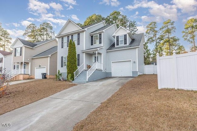 view of front facade with a garage, driveway, and fence