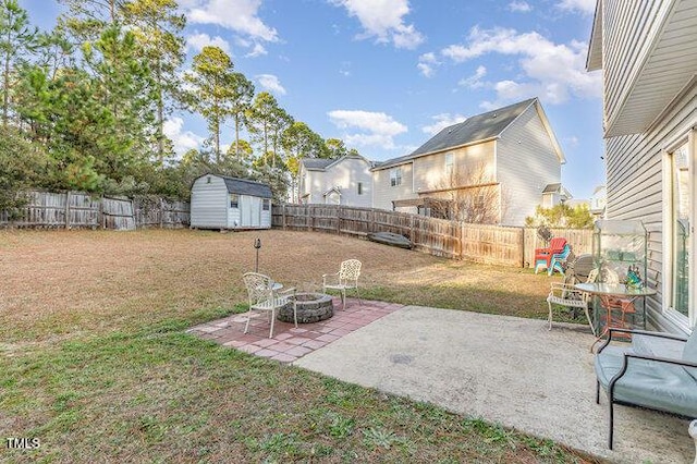 view of yard with an outdoor fire pit, a patio area, a fenced backyard, and a storage shed