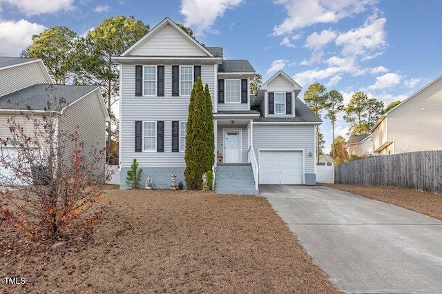 traditional-style home featuring a garage, concrete driveway, and fence