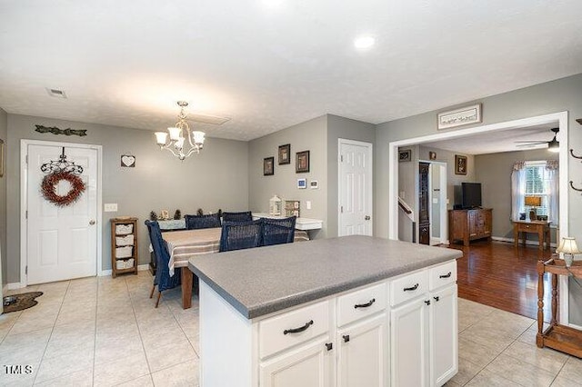 kitchen featuring light tile patterned floors, a kitchen island, visible vents, white cabinets, and dark countertops