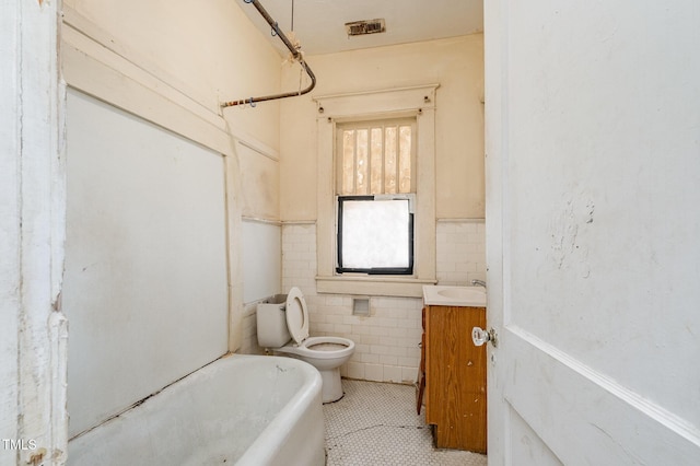 bathroom with vanity, tile walls, tile patterned flooring, toilet, and a tub