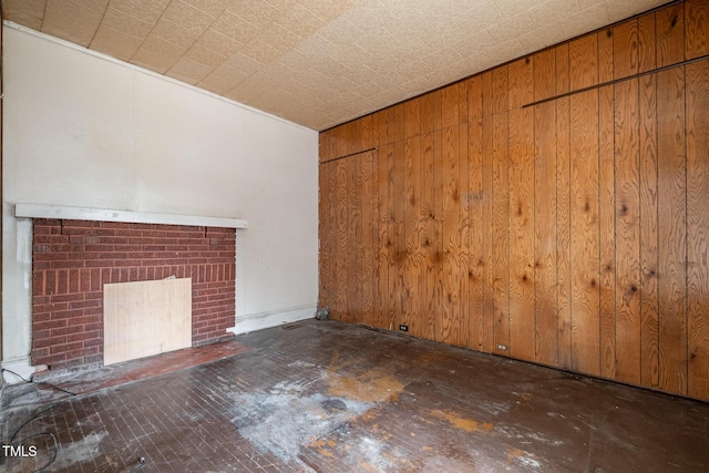 unfurnished living room featuring a fireplace and wooden walls