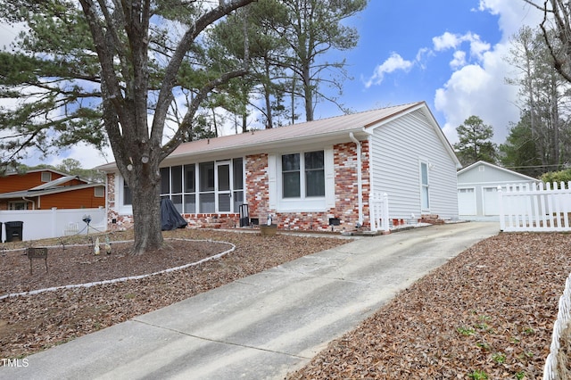 single story home featuring a sunroom, a garage, and an outbuilding