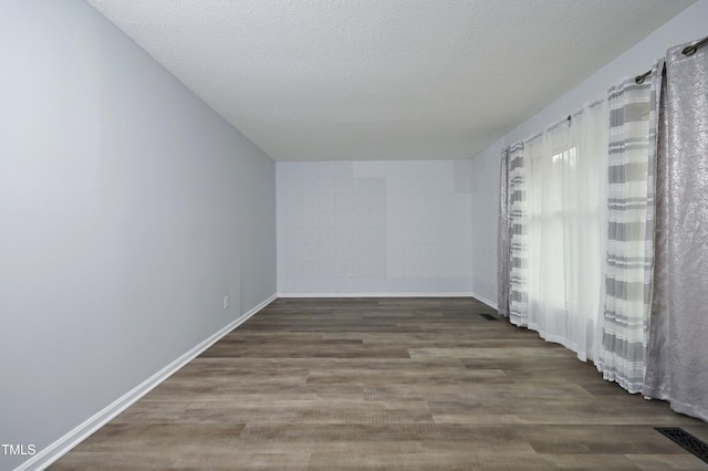 empty room featuring dark wood-type flooring and a textured ceiling