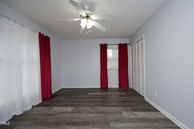 empty room with a textured ceiling, ceiling fan, and dark wood-type flooring