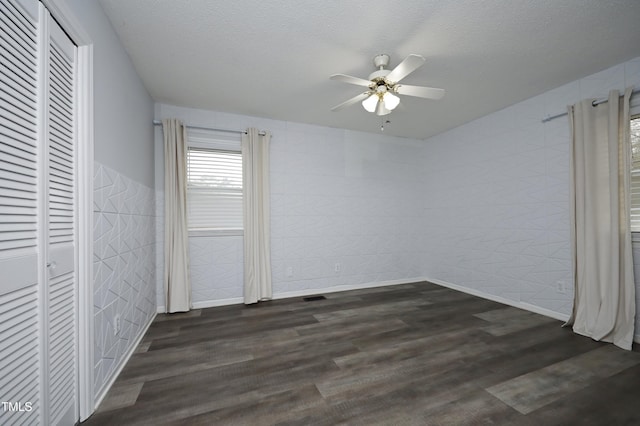 unfurnished bedroom with a textured ceiling, ceiling fan, and dark wood-type flooring