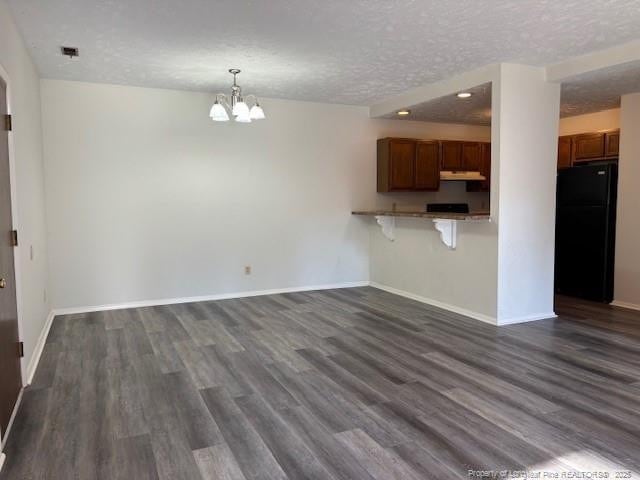 kitchen featuring a kitchen bar, a textured ceiling, kitchen peninsula, and black fridge