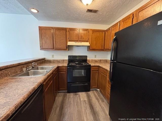 kitchen with dark wood-type flooring, sink, black appliances, and a textured ceiling