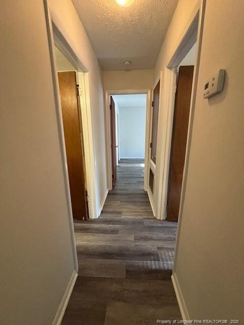 hallway featuring dark hardwood / wood-style floors and a textured ceiling