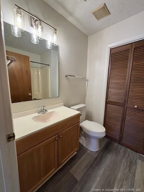 bathroom with a shower, hardwood / wood-style floors, a textured ceiling, toilet, and vanity