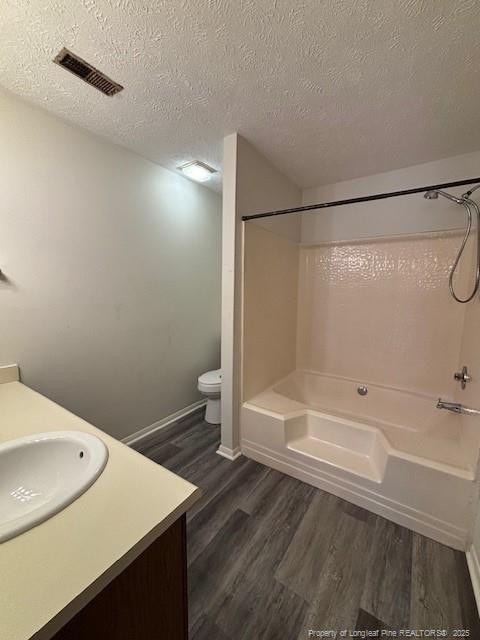 full bathroom featuring vanity, hardwood / wood-style floors, a textured ceiling, and toilet