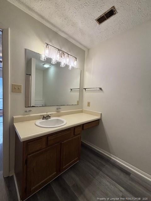 bathroom with hardwood / wood-style floors, vanity, and a textured ceiling