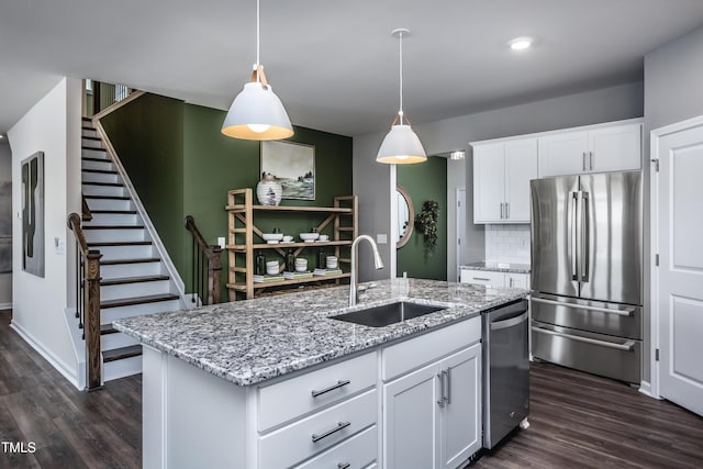 kitchen with sink, stainless steel appliances, decorative backsplash, a kitchen island with sink, and white cabinets