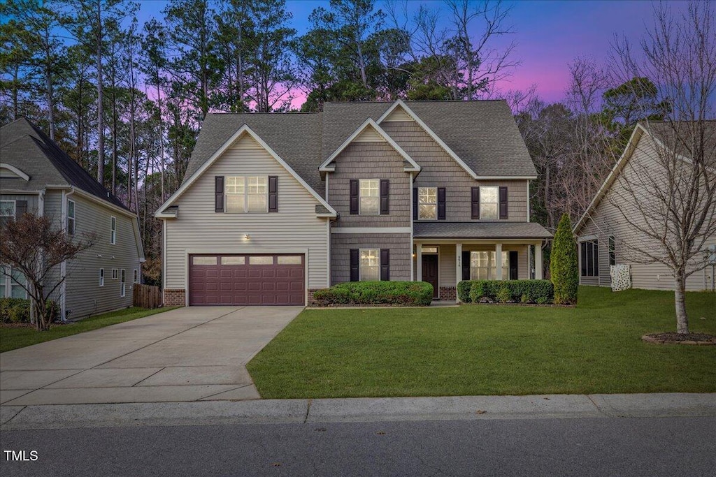 view of front facade featuring a garage, a lawn, and a porch