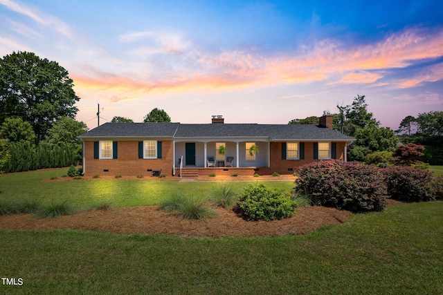 ranch-style home with covered porch and a yard