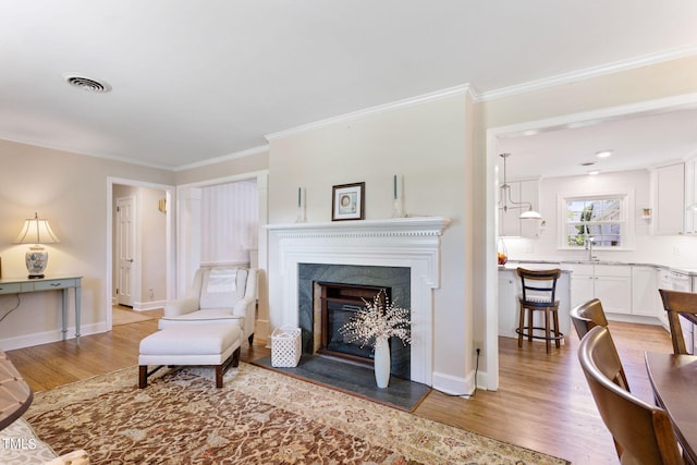 living room featuring light hardwood / wood-style floors, ornamental molding, and sink