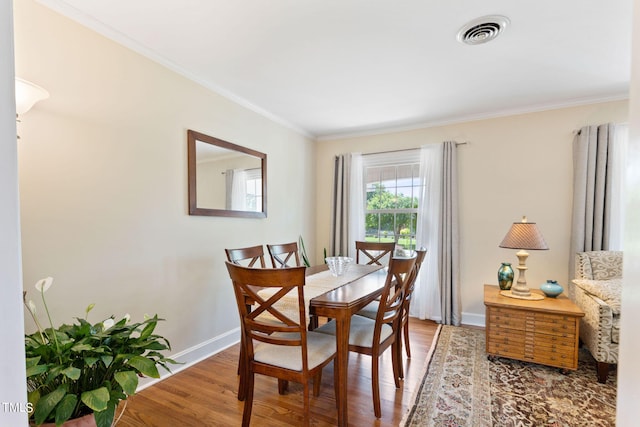 dining area with hardwood / wood-style flooring and crown molding