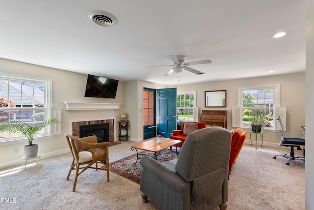 carpeted living room with a brick fireplace and ceiling fan