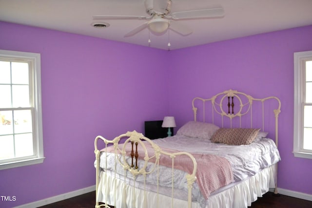 bedroom with multiple windows, dark hardwood / wood-style floors, and ceiling fan