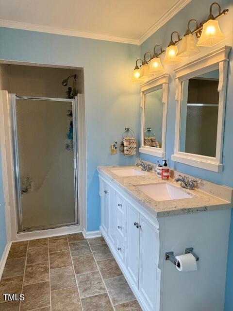 bathroom with vanity, a shower with door, and crown molding