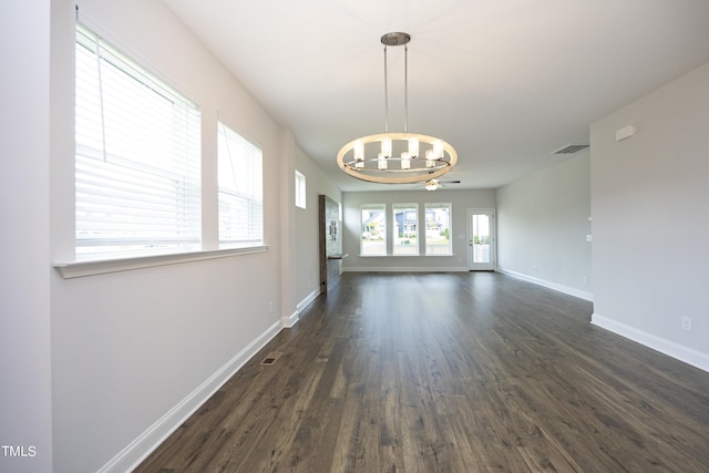 empty room featuring ceiling fan with notable chandelier and dark wood-type flooring