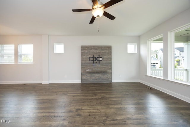 unfurnished living room featuring plenty of natural light, dark wood-type flooring, and ceiling fan