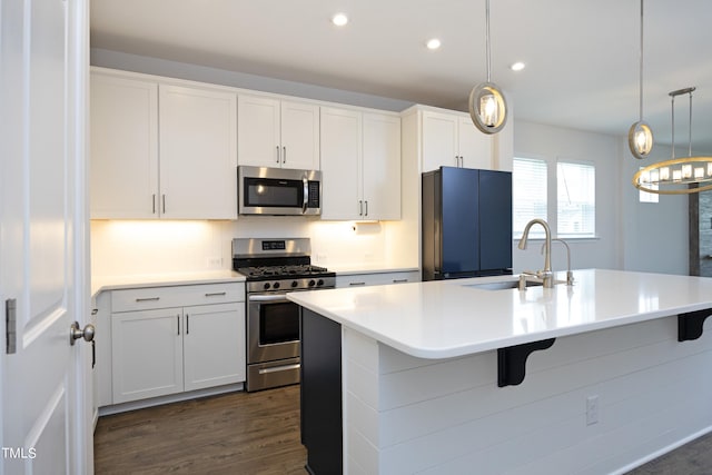 kitchen featuring white cabinetry, sink, an island with sink, decorative light fixtures, and appliances with stainless steel finishes