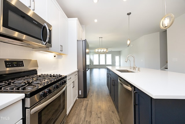 kitchen with pendant lighting, a kitchen island with sink, white cabinets, sink, and stainless steel appliances