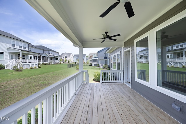 wooden terrace featuring ceiling fan and a lawn