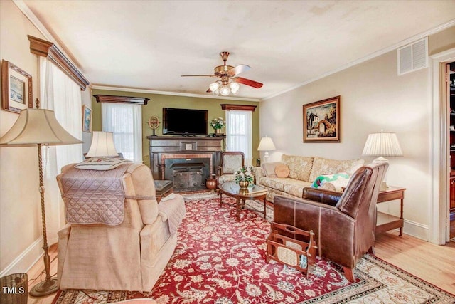 living room featuring crown molding, light hardwood / wood-style flooring, and ceiling fan