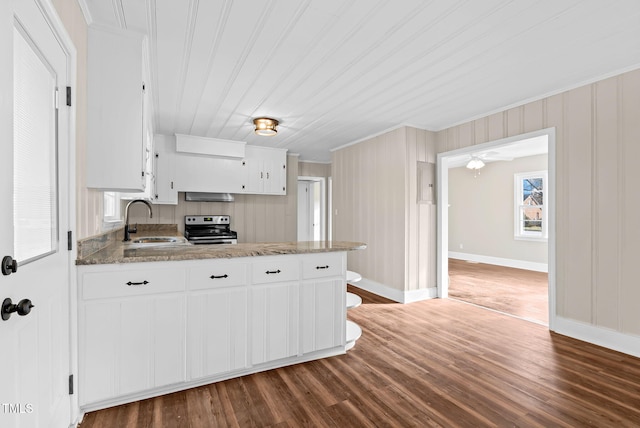 kitchen with light stone countertops, white cabinetry, stainless steel range with electric stovetop, and sink