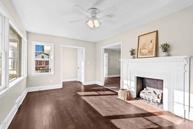 unfurnished living room featuring dark hardwood / wood-style flooring, a brick fireplace, and ceiling fan