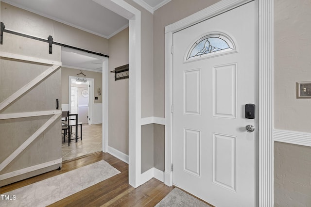 entryway featuring a barn door, wood-type flooring, and ornamental molding