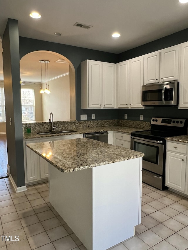 kitchen with sink, decorative light fixtures, a kitchen island, stainless steel appliances, and white cabinets